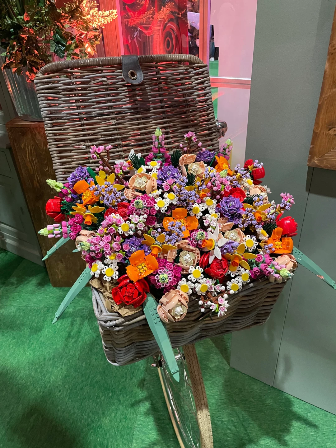 Een mand gevuld met kleurrijke LEGO bloemen op een fiets.